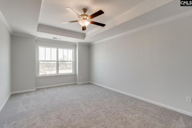 carpeted empty room featuring visible vents, a tray ceiling, baseboards, and ornamental molding