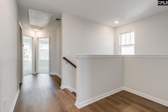 corridor featuring dark wood-type flooring, an upstairs landing, attic access, and baseboards