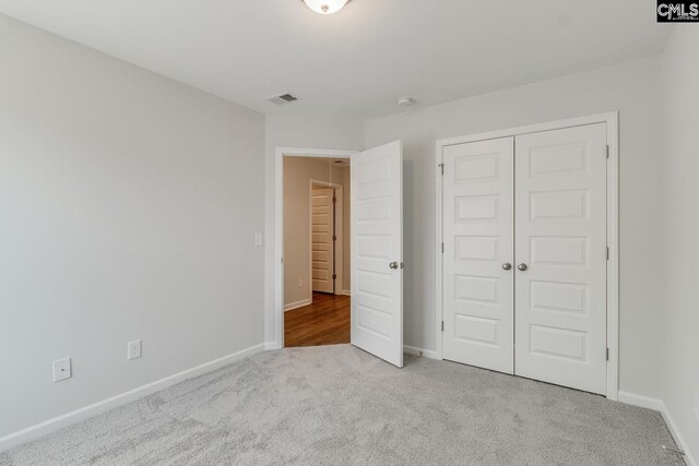 unfurnished bedroom featuring a closet, carpet flooring, visible vents, and baseboards