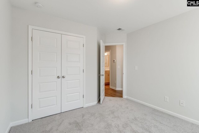 unfurnished bedroom featuring carpet floors, visible vents, baseboards, and a closet