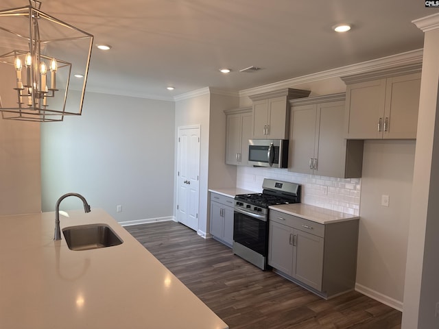 kitchen with a sink, light countertops, ornamental molding, appliances with stainless steel finishes, and gray cabinets