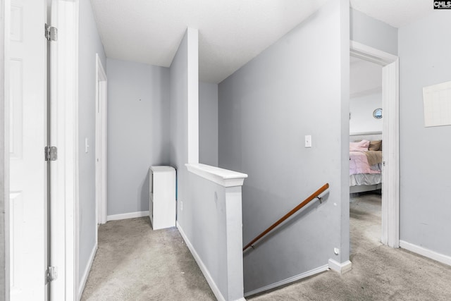 hallway with a textured ceiling and light colored carpet