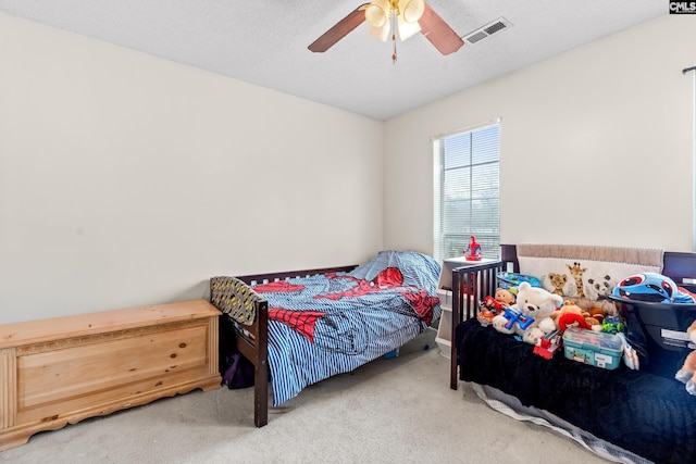 carpeted bedroom with a textured ceiling and ceiling fan