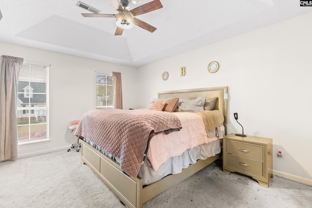 carpeted bedroom featuring a tray ceiling and ceiling fan