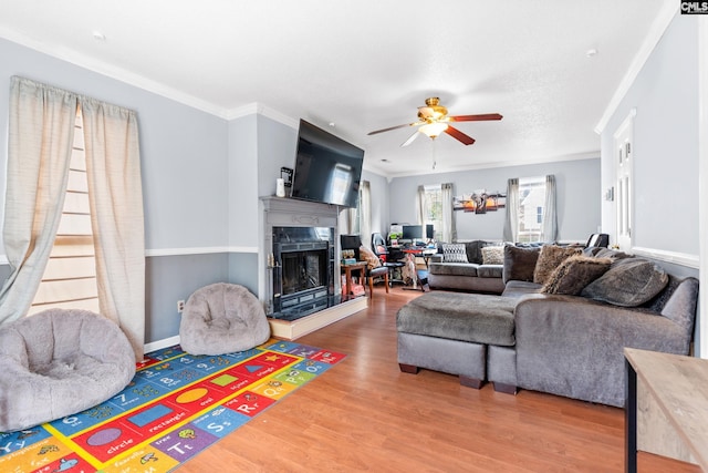 living room featuring hardwood / wood-style floors, ceiling fan, ornamental molding, and a fireplace