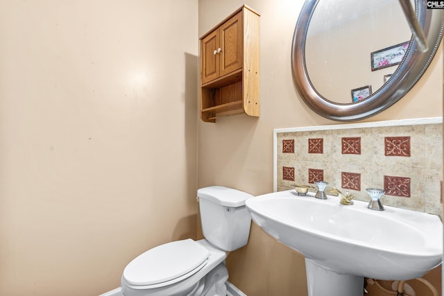 bathroom with decorative backsplash, toilet, and sink