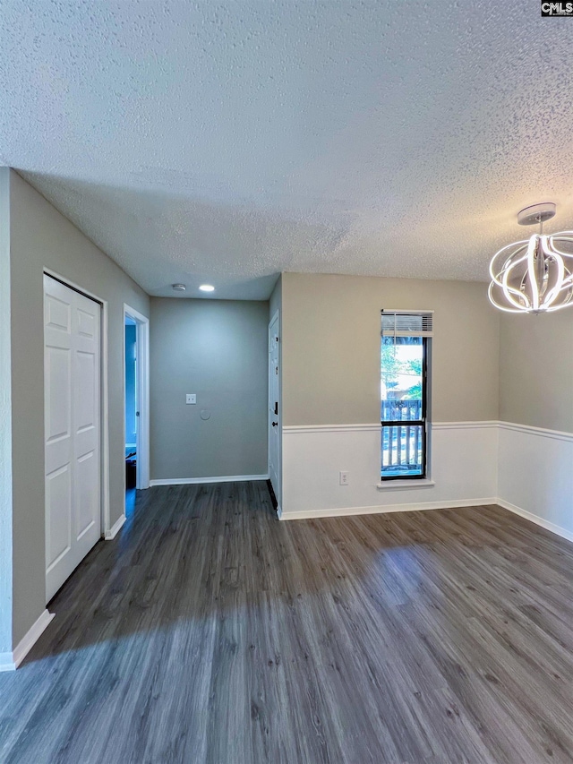 unfurnished room with a textured ceiling and dark wood-type flooring