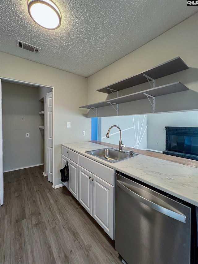 kitchen featuring light stone counters, a textured ceiling, dishwasher, white cabinets, and sink