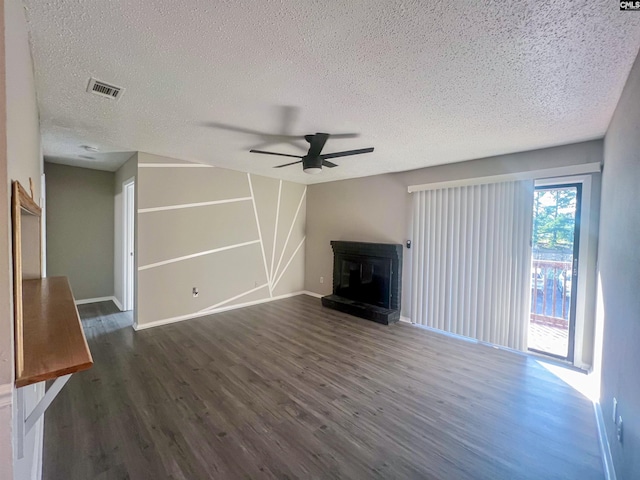 unfurnished living room with a brick fireplace, dark wood-type flooring, ceiling fan, and a textured ceiling