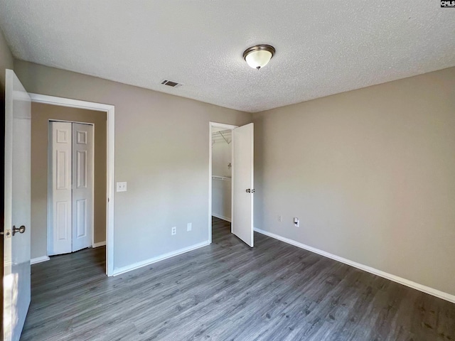 unfurnished bedroom with dark wood-type flooring, a textured ceiling, and a closet