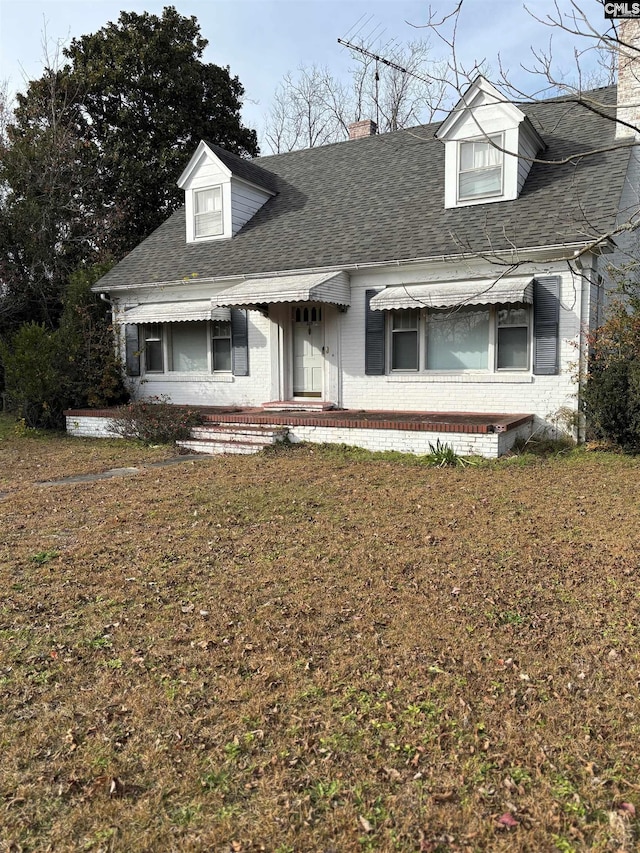 cape cod home with a front lawn