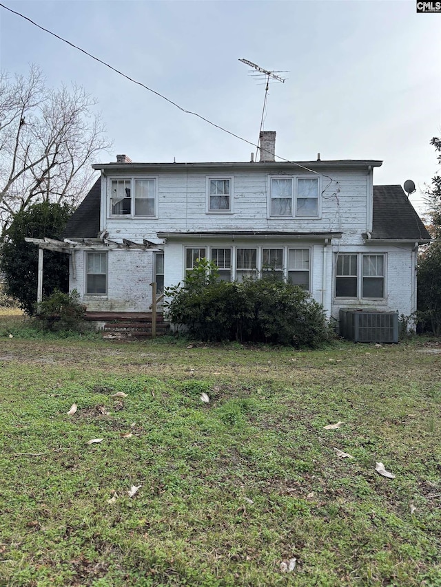 rear view of house with a yard and central AC