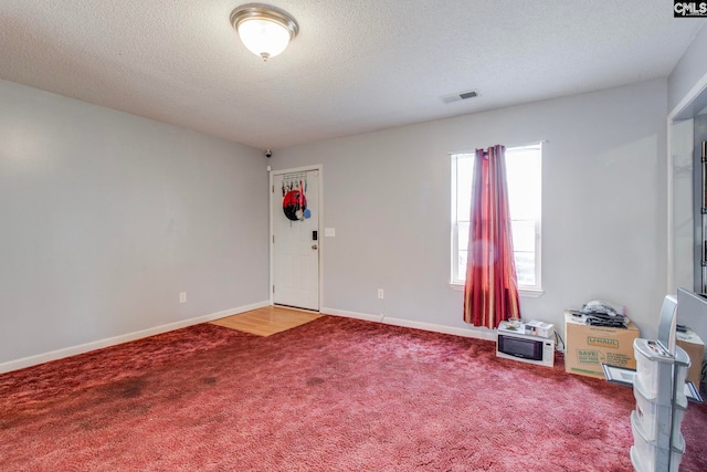 carpeted spare room featuring a textured ceiling