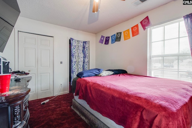 carpeted bedroom featuring ceiling fan and a textured ceiling