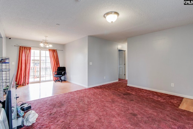 carpeted empty room with a textured ceiling and a chandelier