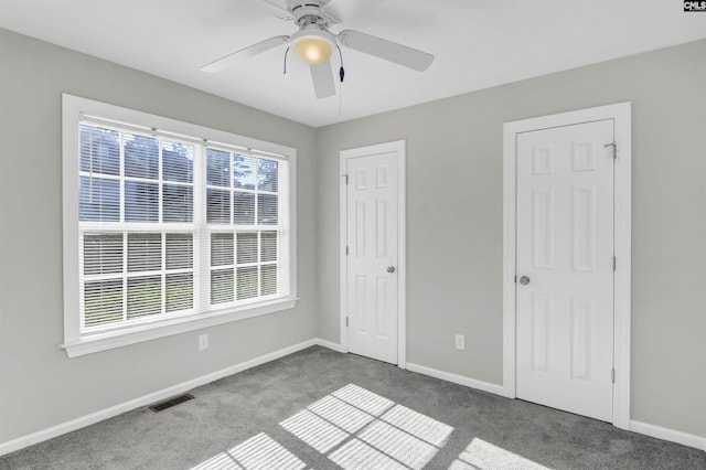 unfurnished bedroom with dark colored carpet and ceiling fan