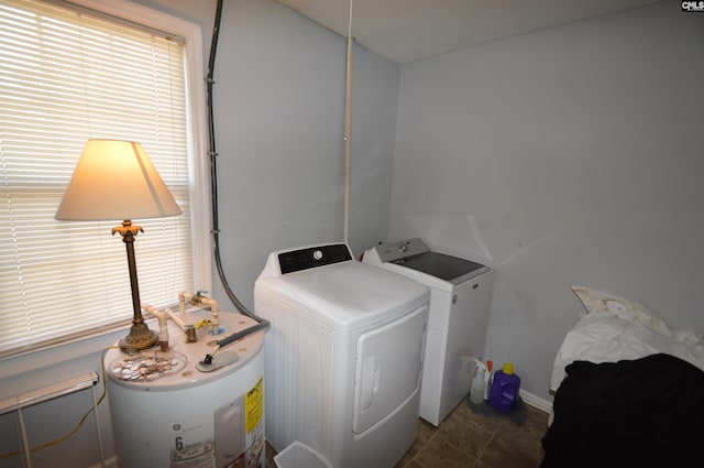 laundry area featuring independent washer and dryer, dark tile patterned flooring, and water heater