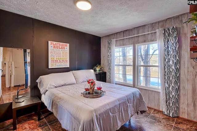 bedroom featuring wood walls and a textured ceiling