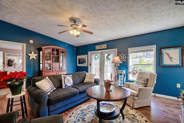 living room with ceiling fan, french doors, dark hardwood / wood-style flooring, lofted ceiling, and a textured ceiling