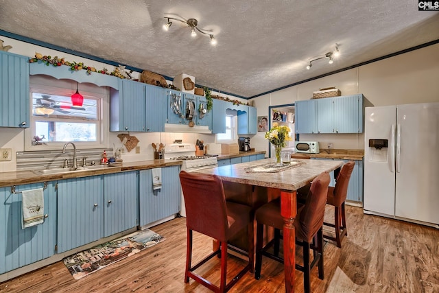 kitchen with sink, blue cabinets, a textured ceiling, lofted ceiling, and white appliances