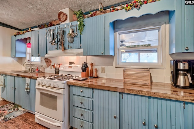 kitchen featuring white gas stove, a healthy amount of sunlight, a textured ceiling, and sink