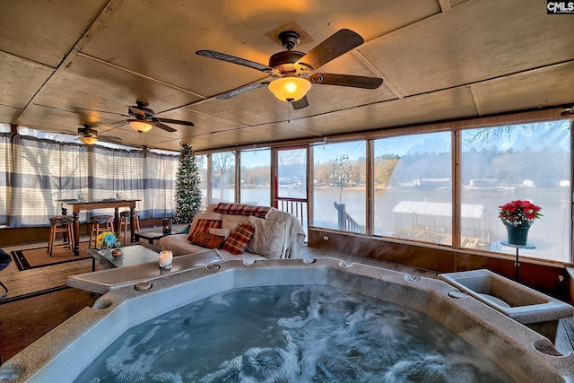 sunroom / solarium featuring a water view and a hot tub