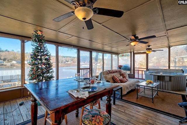 sunroom / solarium with ceiling fan and a water view