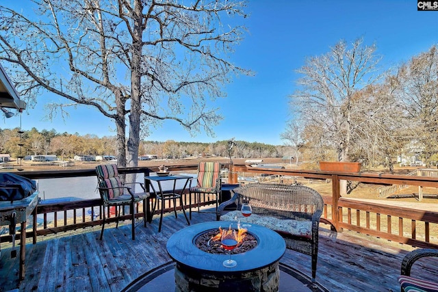 wooden terrace featuring a water view and an outdoor fire pit