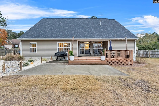 back of property with a lawn, a patio area, and a deck