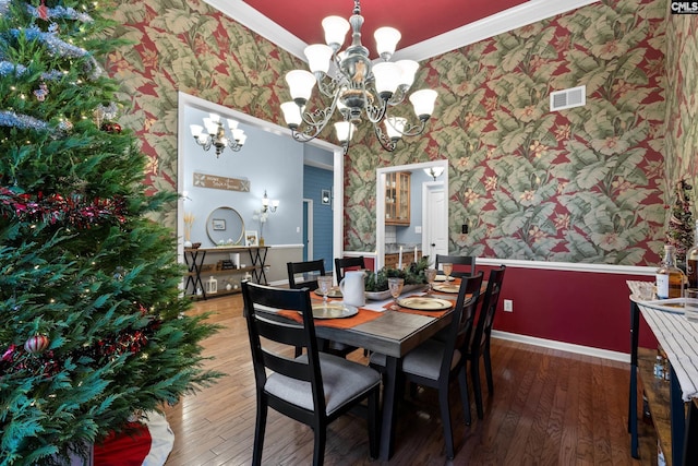 dining room with crown molding, dark hardwood / wood-style floors, and an inviting chandelier