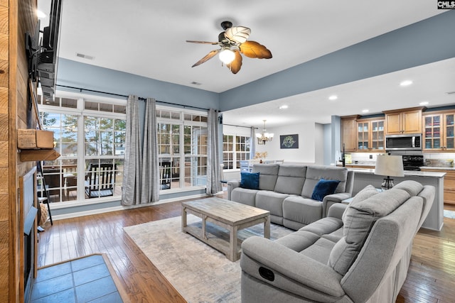 living room featuring ceiling fan with notable chandelier and dark hardwood / wood-style floors