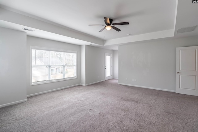 carpeted empty room with a tray ceiling and ceiling fan