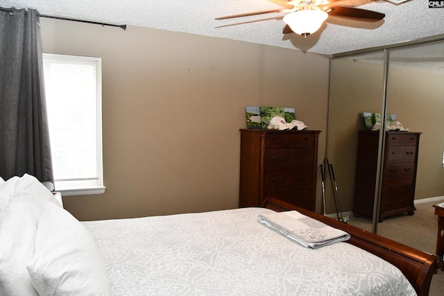 carpeted bedroom with ceiling fan, a textured ceiling, and multiple windows