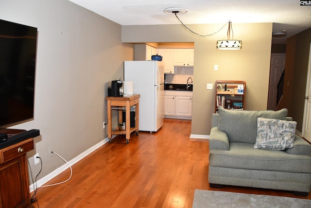 living room featuring hardwood / wood-style flooring, sink, and a textured ceiling