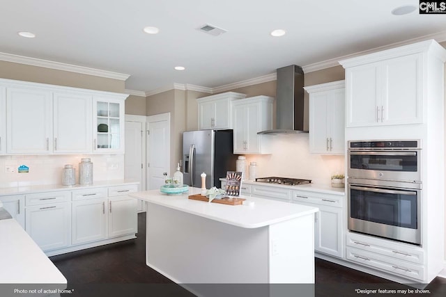 kitchen with wall chimney exhaust hood, stainless steel appliances, crown molding, white cabinets, and dark hardwood / wood-style floors