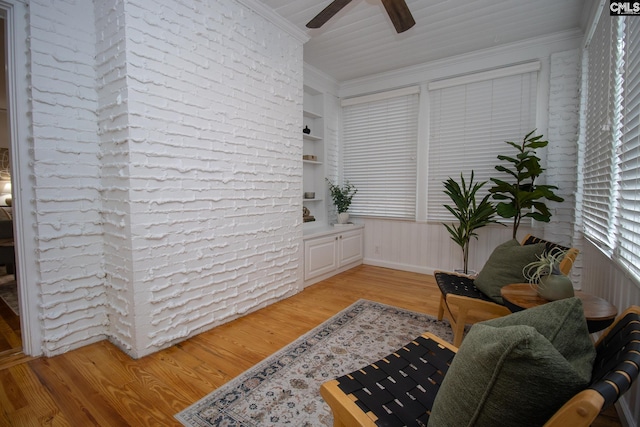 living area with built in shelves, light hardwood / wood-style flooring, and ornamental molding