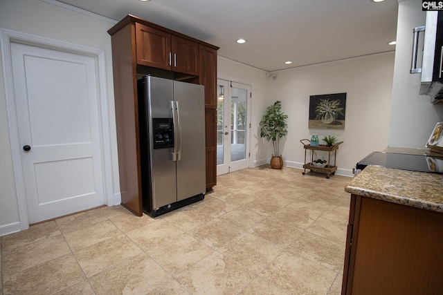 kitchen featuring dark stone countertops and stainless steel refrigerator with ice dispenser