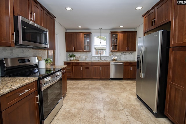 kitchen featuring pendant lighting, backsplash, sink, appliances with stainless steel finishes, and light stone counters