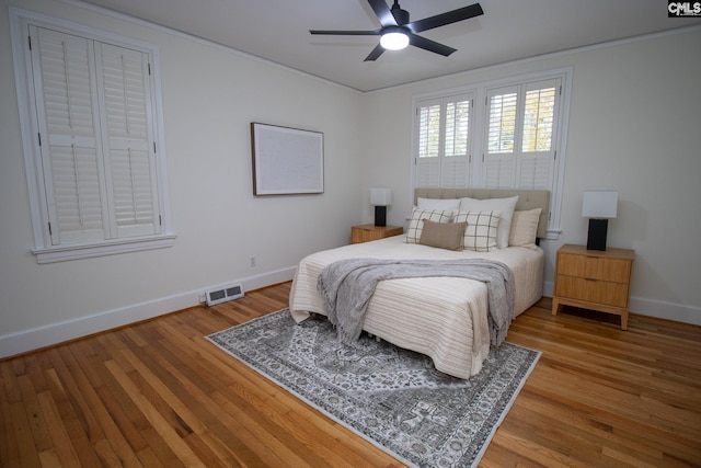 bedroom with hardwood / wood-style flooring, ceiling fan, and ornamental molding