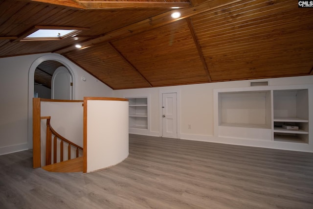 additional living space with wood-type flooring, built in shelves, wooden ceiling, and vaulted ceiling with skylight