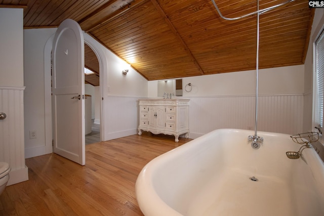 bathroom featuring hardwood / wood-style floors, lofted ceiling with beams, wood ceiling, and a tub