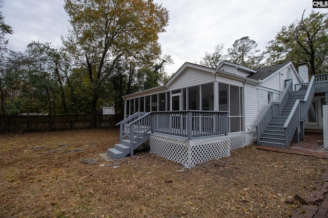 back of property with a wooden deck and a sunroom