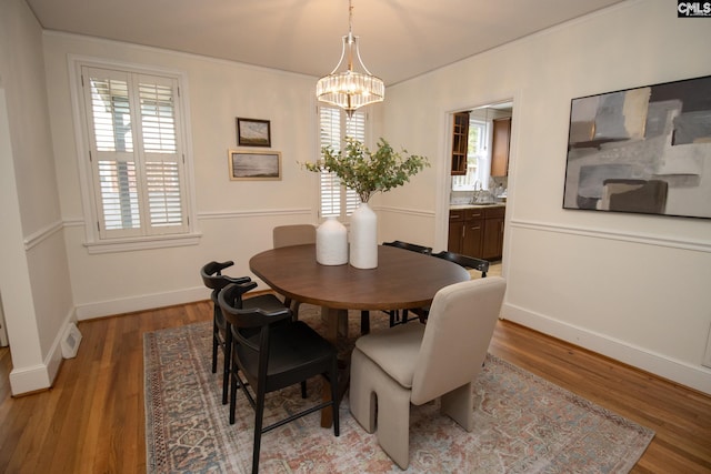 dining room featuring wood-type flooring, sink, and a chandelier