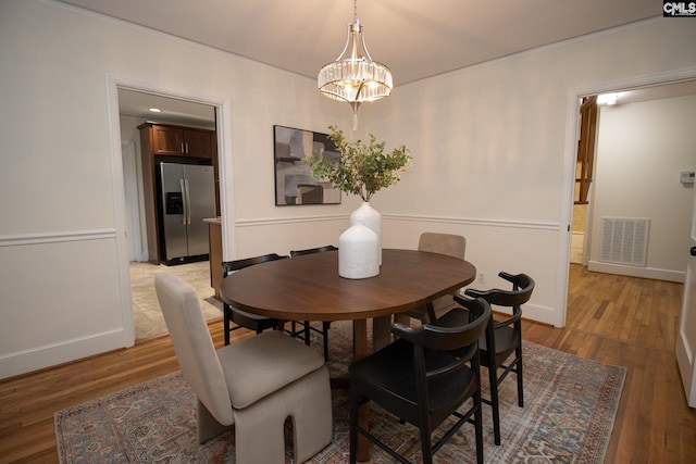 dining space with hardwood / wood-style flooring and a notable chandelier