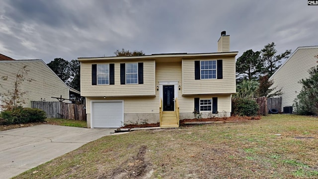 split foyer home with a front yard, a garage, and central air condition unit