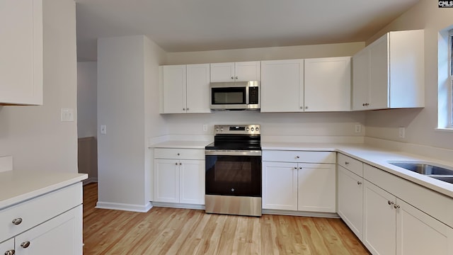 kitchen featuring white cabinetry, sink, appliances with stainless steel finishes, and light hardwood / wood-style flooring