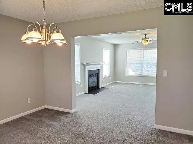 unfurnished living room featuring a textured ceiling, carpet floors, and ceiling fan with notable chandelier