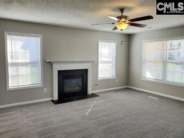 unfurnished living room featuring carpet flooring, ceiling fan, and a textured ceiling