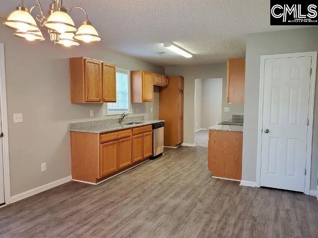 kitchen with hardwood / wood-style floors, an inviting chandelier, sink, appliances with stainless steel finishes, and decorative light fixtures