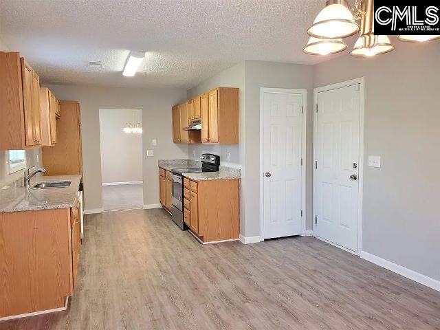 kitchen with a textured ceiling, sink, light wood-type flooring, and stainless steel range with electric cooktop